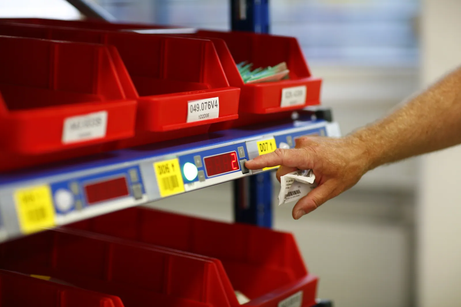 Operator using a pick-to-light system with illuminated shelf displays guiding item selection