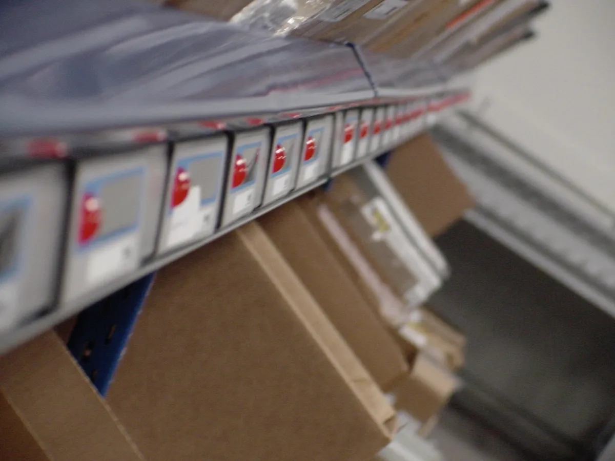 Row of pick-to-light modules mounted along a shelf edge, each showing a quantity display and red confirmation button