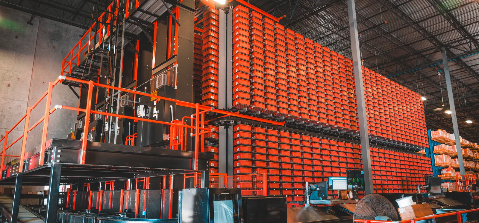 Mini load tote AS/RS with stacked bins in high-density racking feeding an integrated goods-to-person pick station and conveyor takeaway
